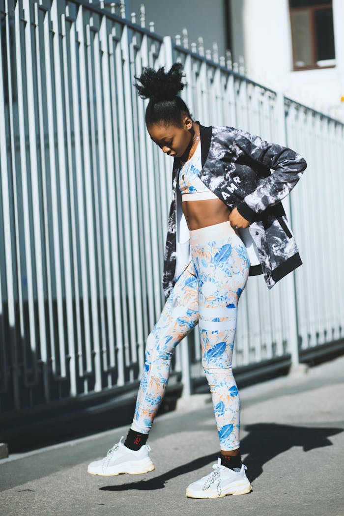 Stylish woman in workout gear posing confidently on an urban street.