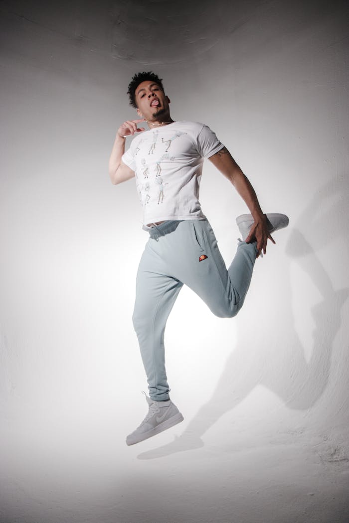 Energetic male model leaps in fashionable activewear during a photoshoot, showcasing motion and style.